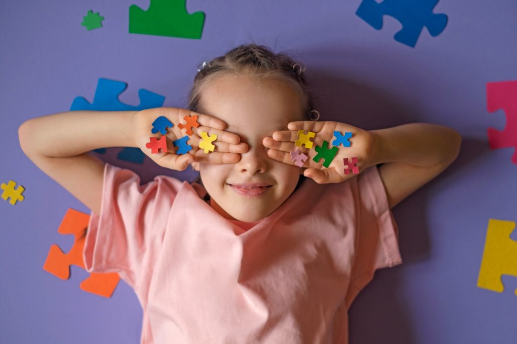 The child holds colored puzzle pieces in his hands, closing his eyes.